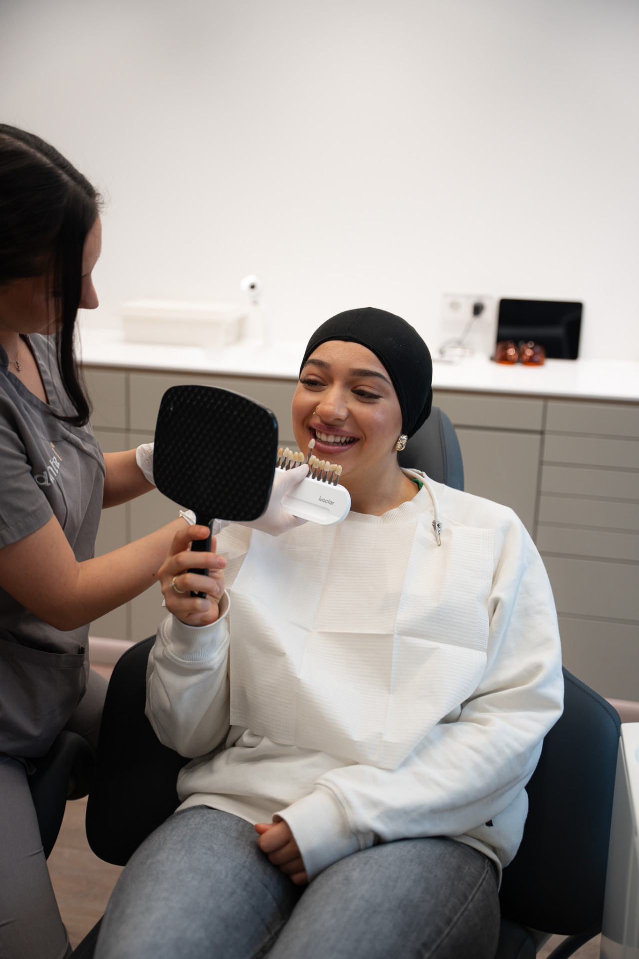 Patientin vergleicht Zahnfarbe mit Shade-Guide